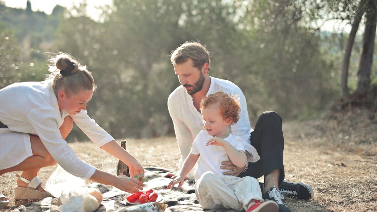 Happy family enjoying a sunny outdoor picnic in a serene natural setting.